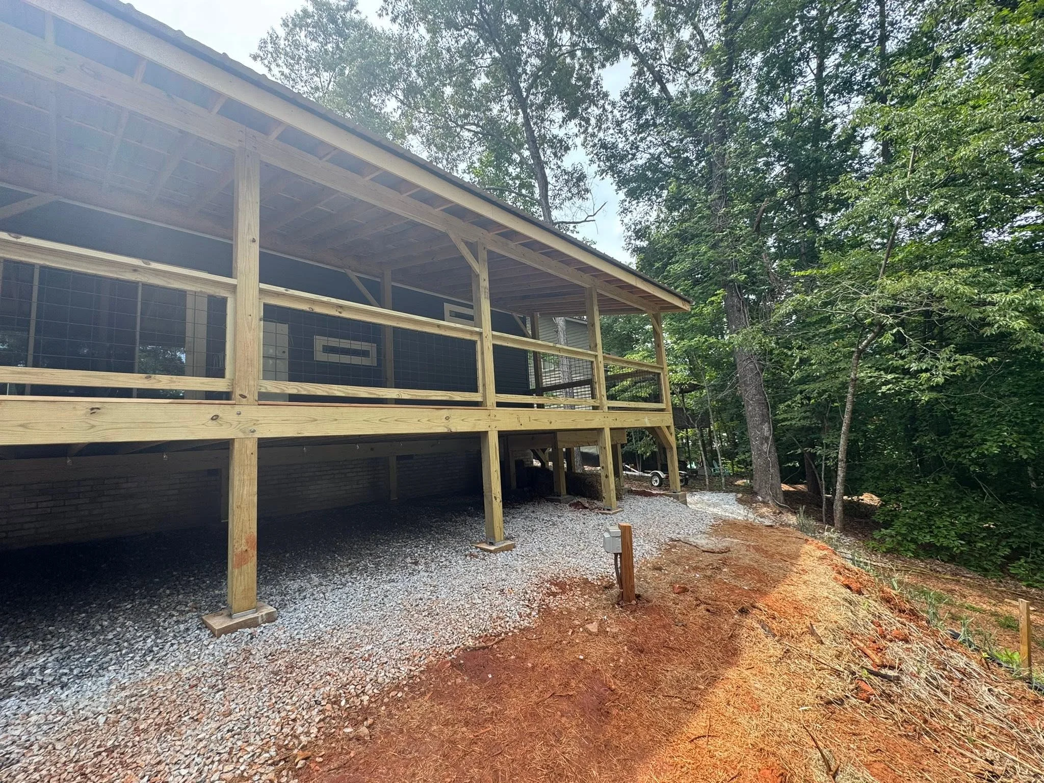 Elevated wooden deck with screened porch, pressure-treated framing, metal roof, and gravel foundation