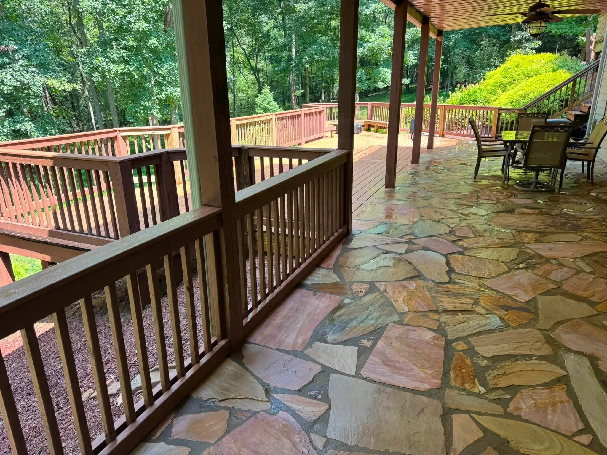 Multi-level cedar deck with dark railings and flagstone patio under covered pergola