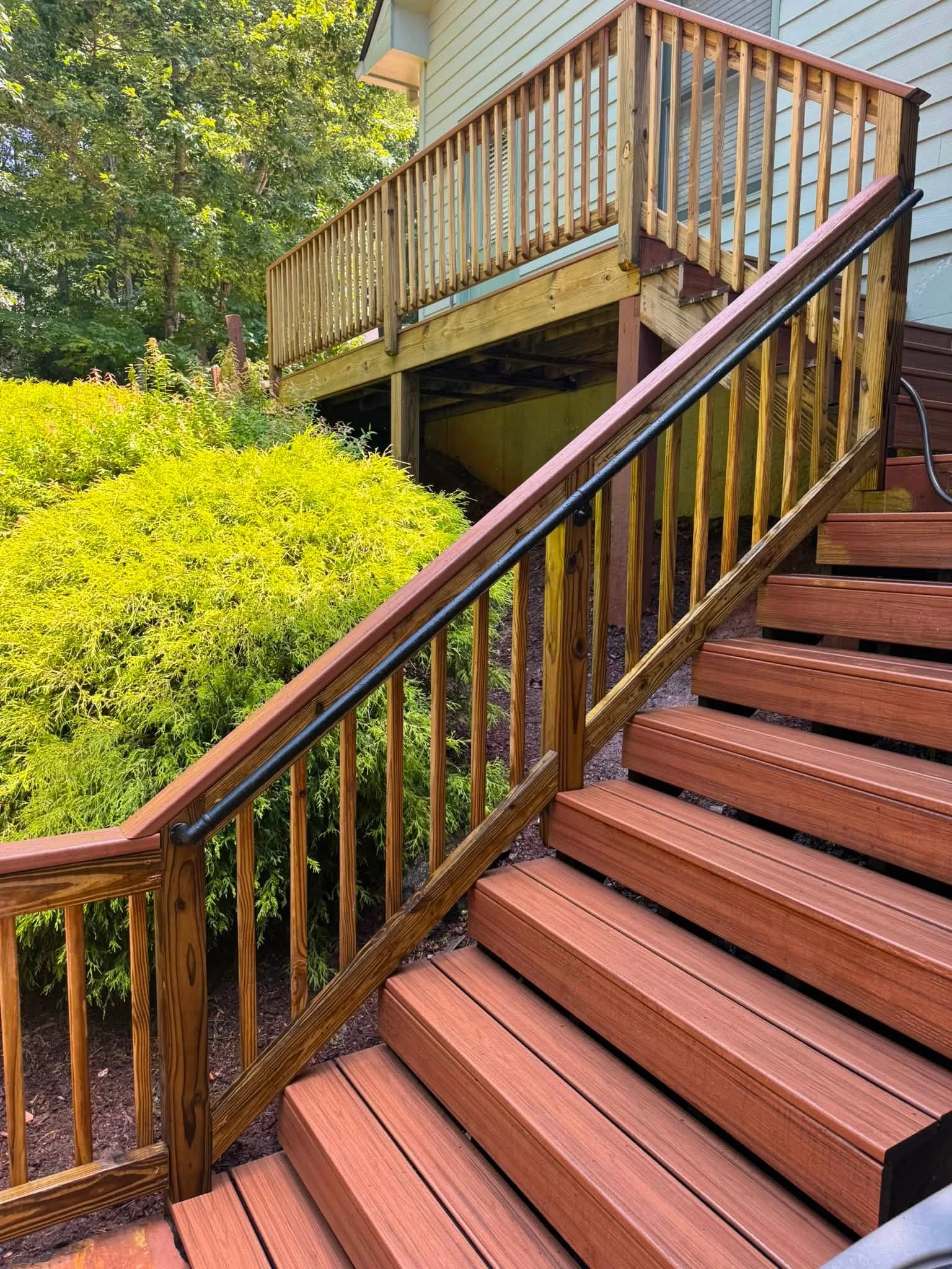Multi-level composite deck with wooden balusters, metal handrails, and grand staircase