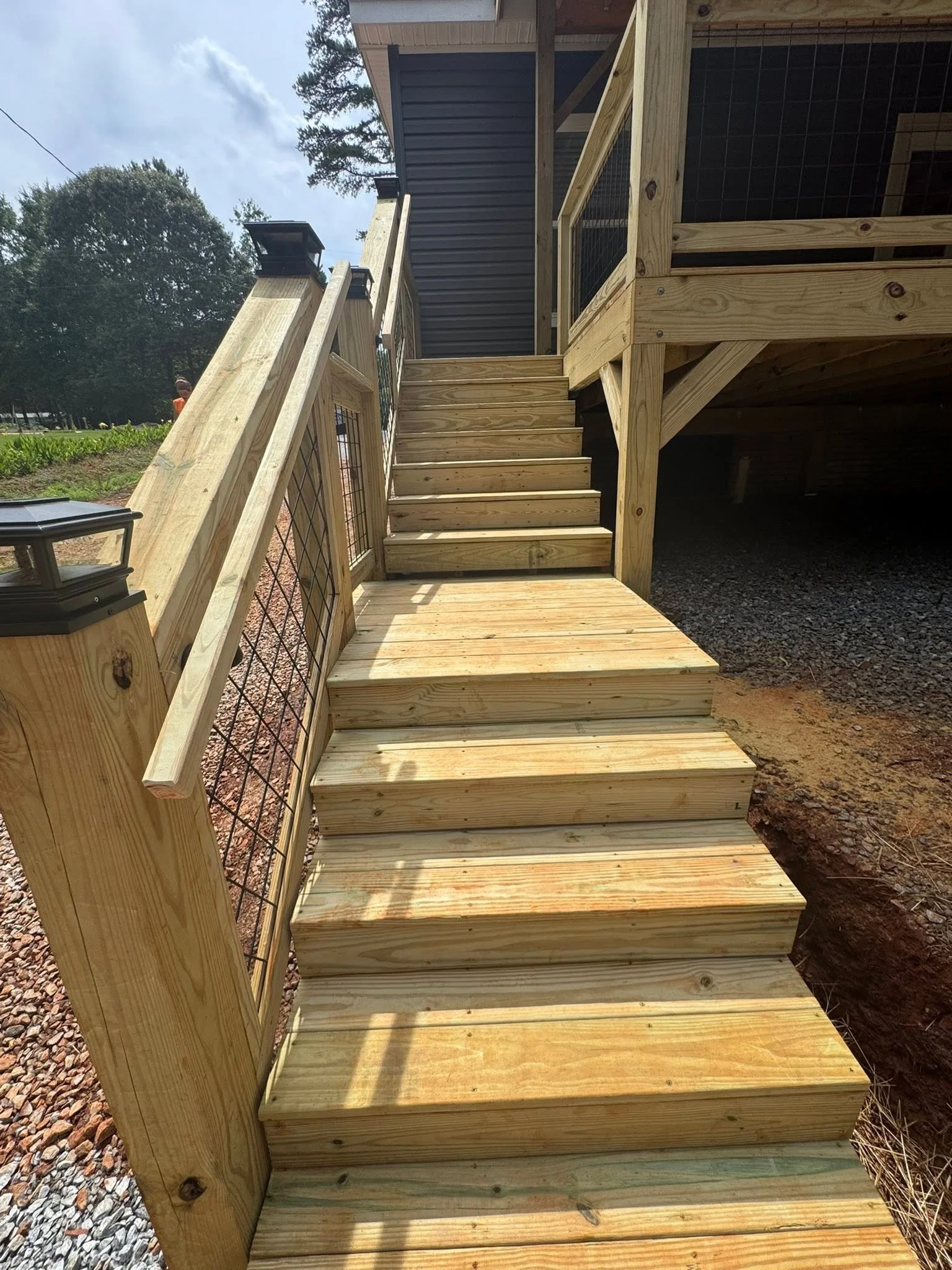 Pressure-treated wood deck stairs with metal railing and solid wood railings leading to elevated platform