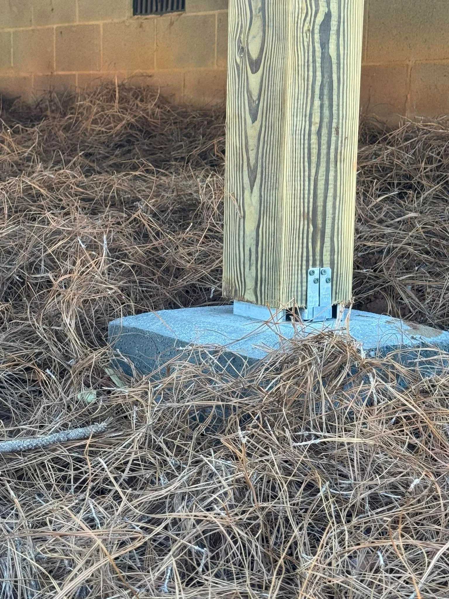 Pressure-treated deck post with metal base on concrete footing and gravel base