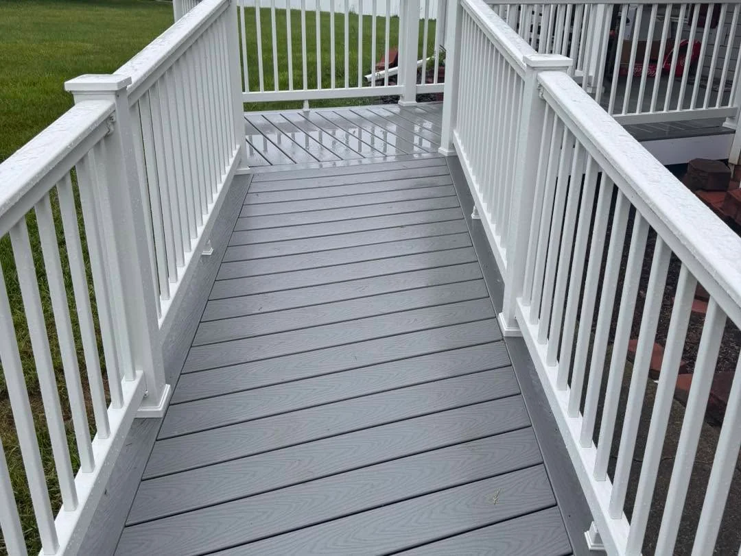 Gray composite deck with white vinyl railing and vertical balusters, gated entry