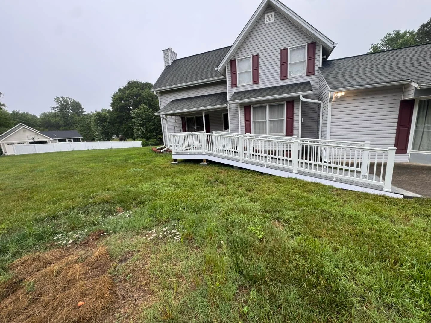 White vinyl railing deck with balusters attached to two-story home with gray siding