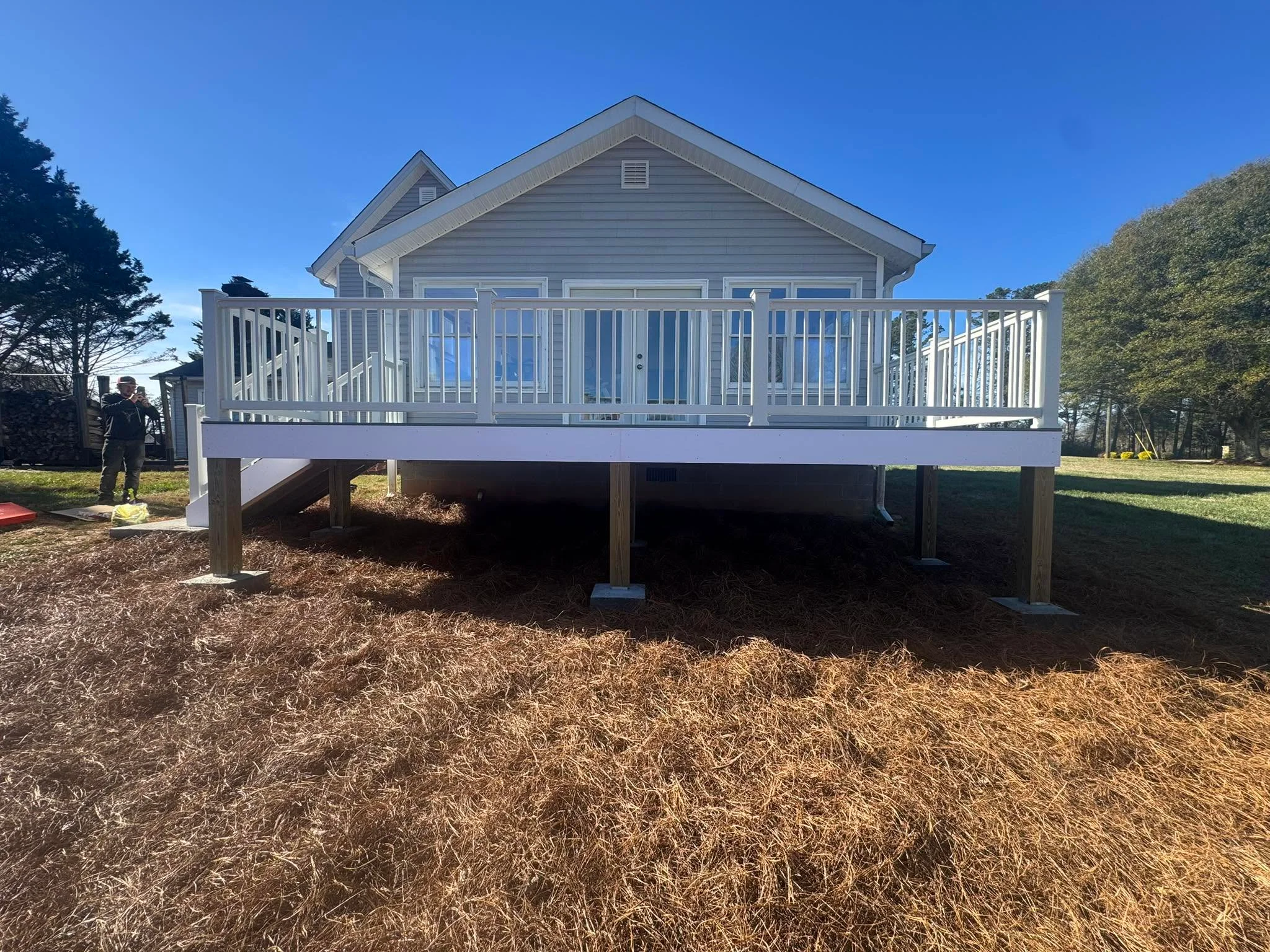 Elevated deck with white railings and wooden post supports under residential home