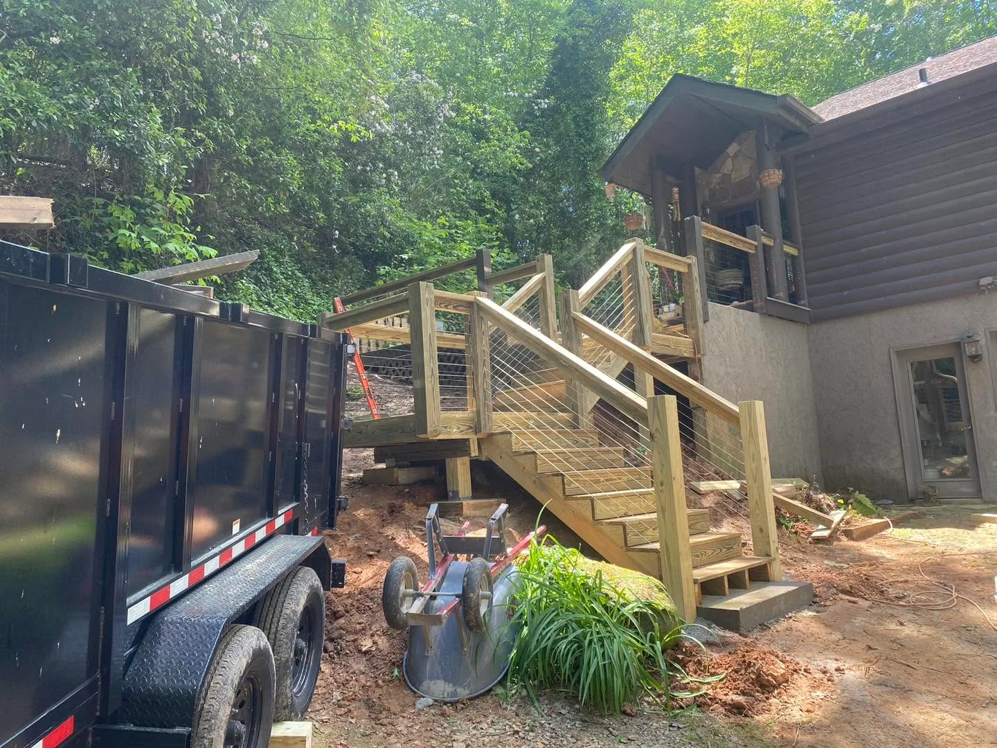 Elevated wooden deck with cable railing and angled stairs under construction