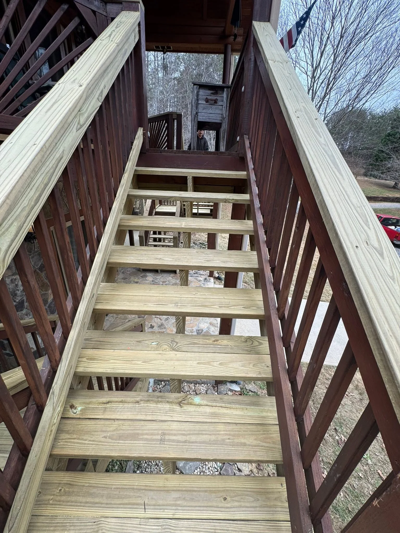 New pressure-treated wood deck stairs with railings, viewed from above looking down