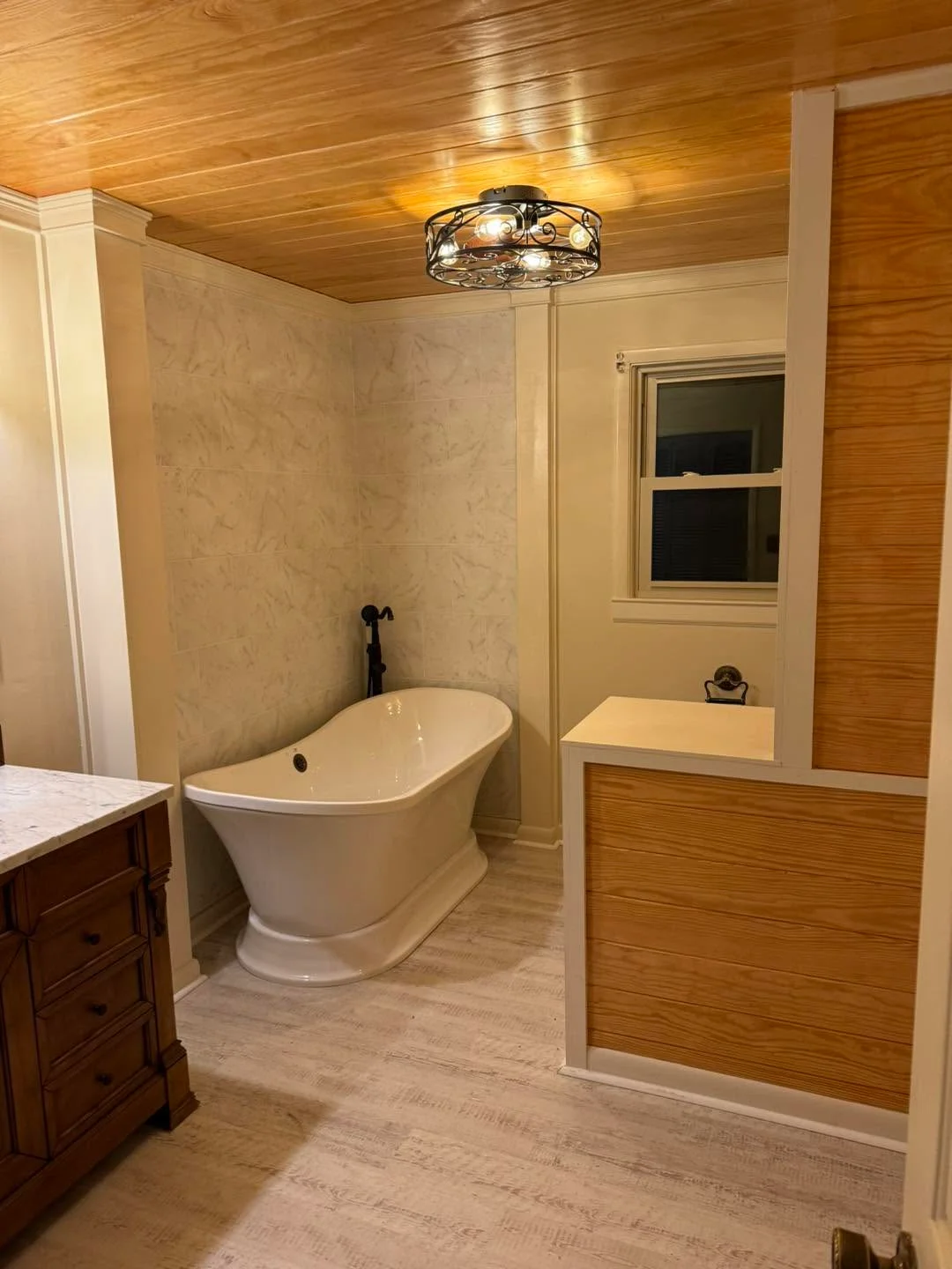 Freestanding tub, wood ceiling, marble tile walls, glass shower enclosure, recessed lighting