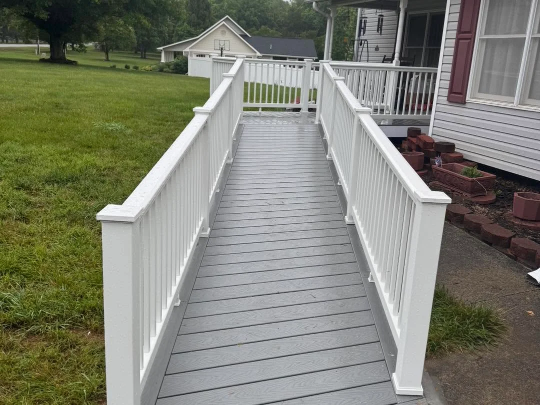 Gray composite deck with white vinyl railing and handrails extending from house