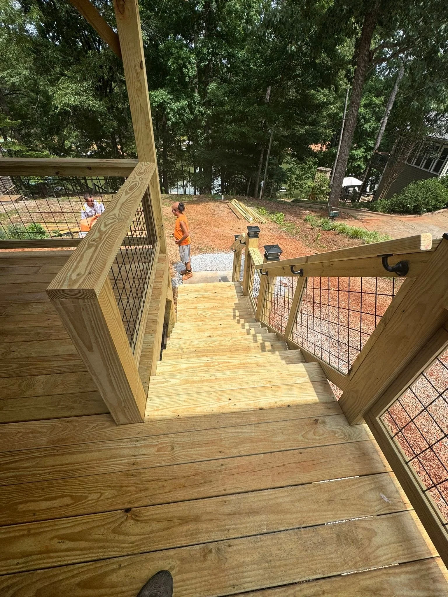 Wooden deck with metal cable railing, stairs, and pressure-treated lumber construction