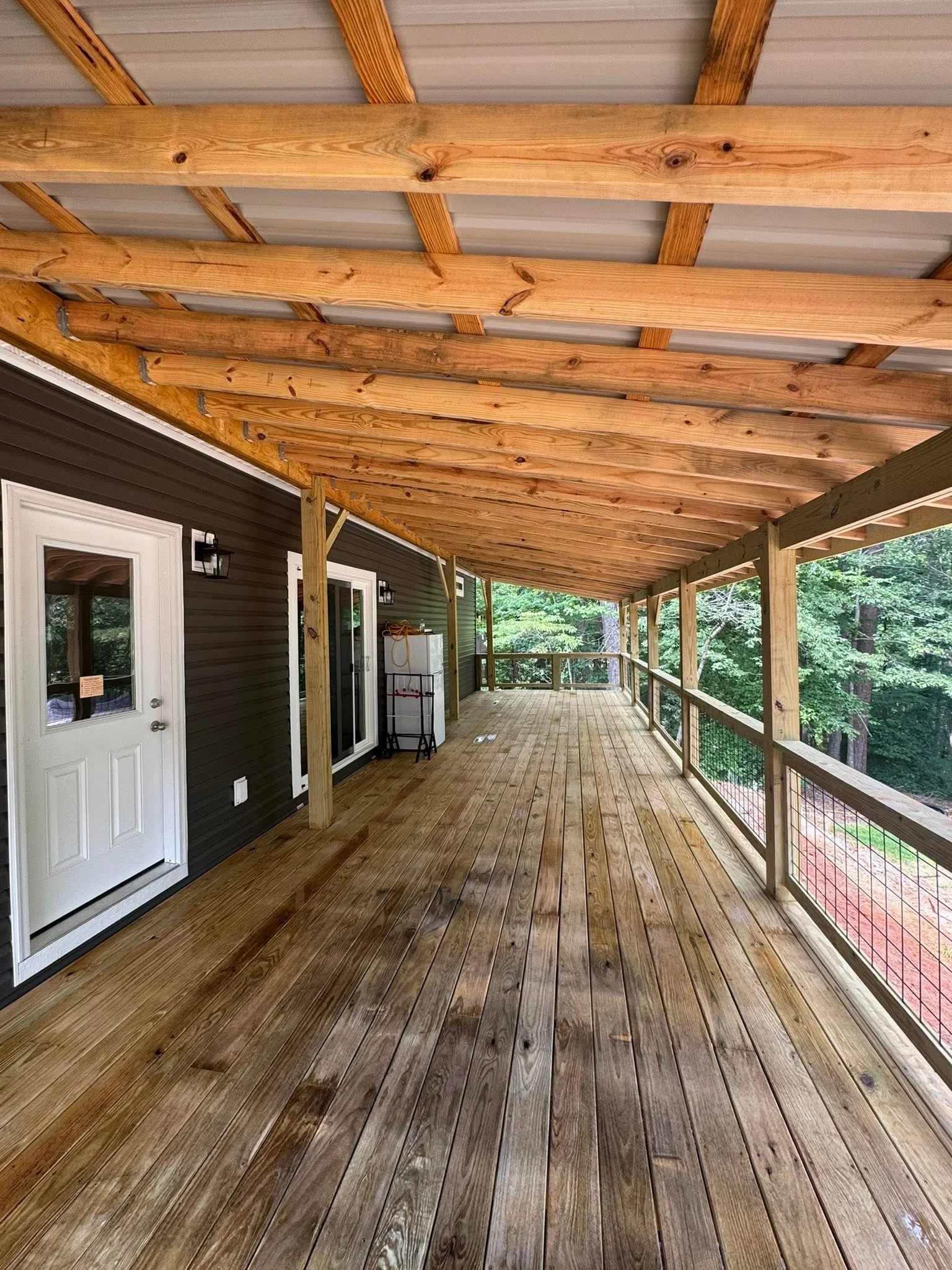 Covered deck with exposed wood beam pergola, composite decking, and metal mesh railings