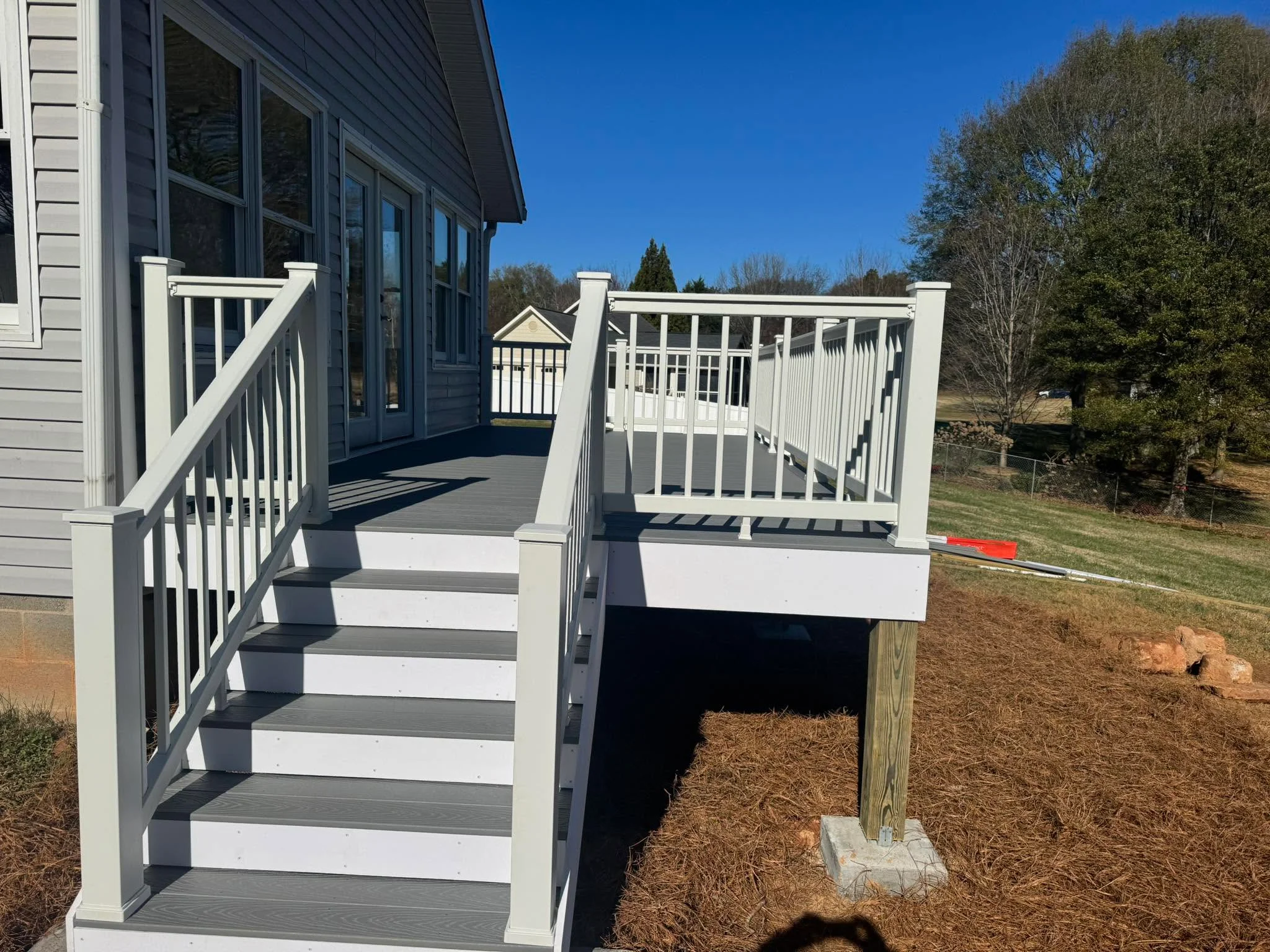 Two-level composite deck with gray boards, white vinyl railings, and white posts with stairs