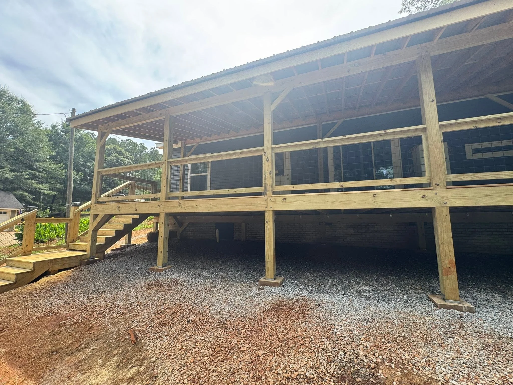 Elevated wooden deck with screened porch, metal roof, and cable railing system