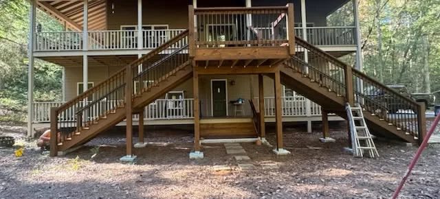 Multi-level wooden deck with dual staircases, metal railings, and support posts